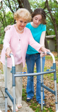 Caregiver assisting an elderly woman to walk