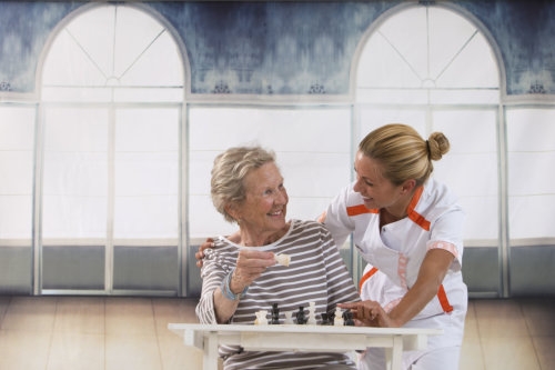 caregiver and elderly woman playing chess